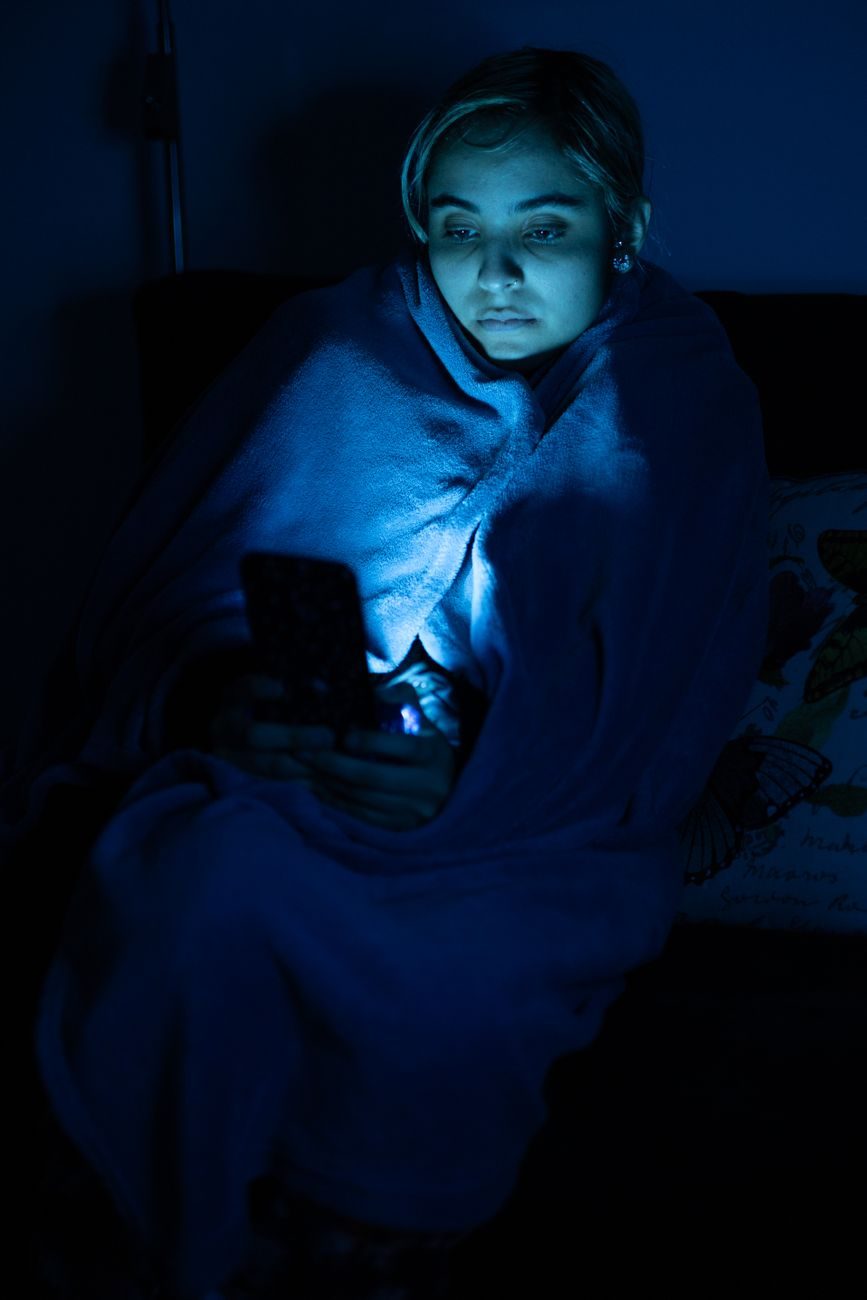 Smartphone-Nutzung im abgedunkelten Raum, wobei die Blinzelrate sinkt und die Augen austrocknen können